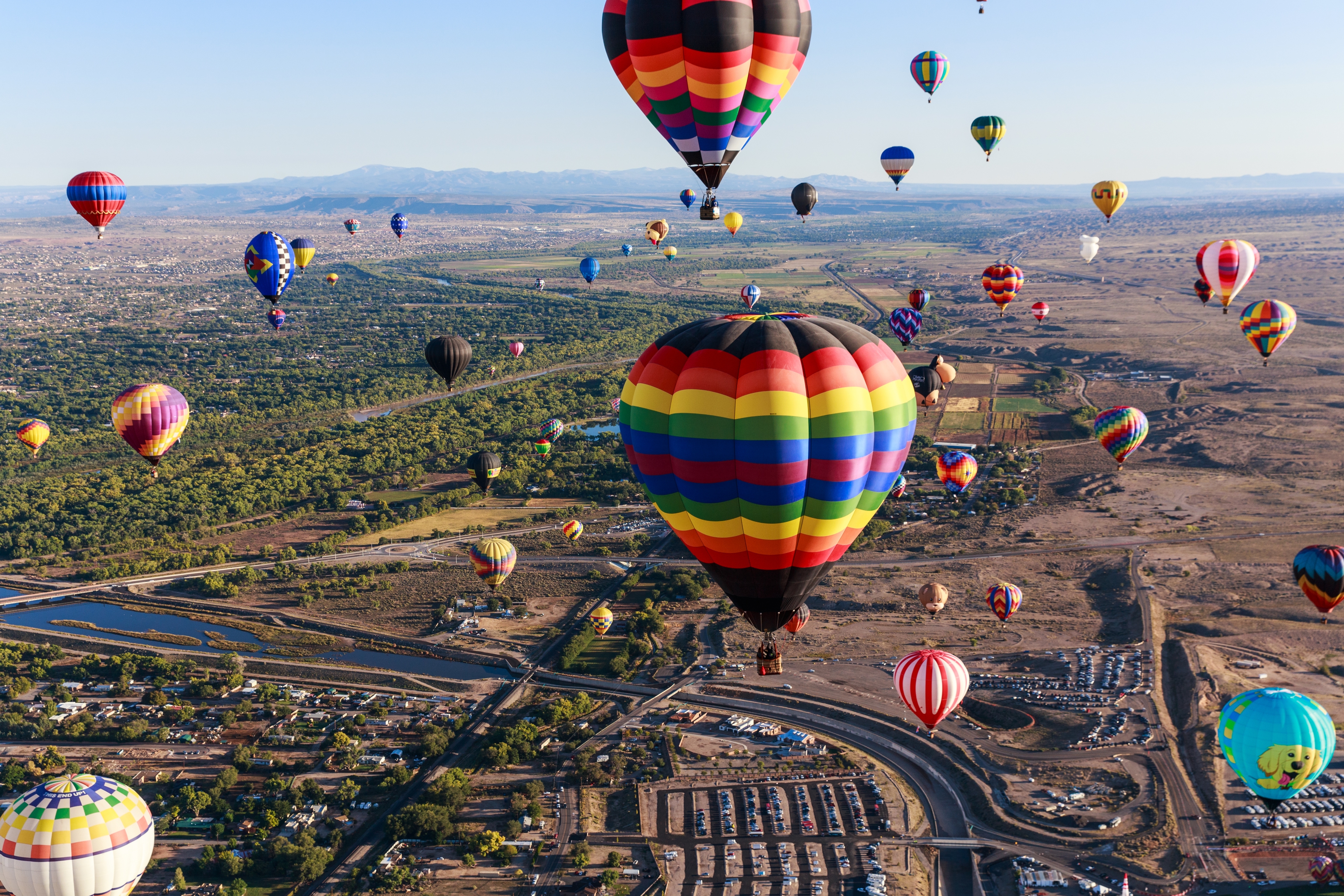 Albuquerque hot air balloons floating over desert landscape during sunrise at the Balloon Fiesta.