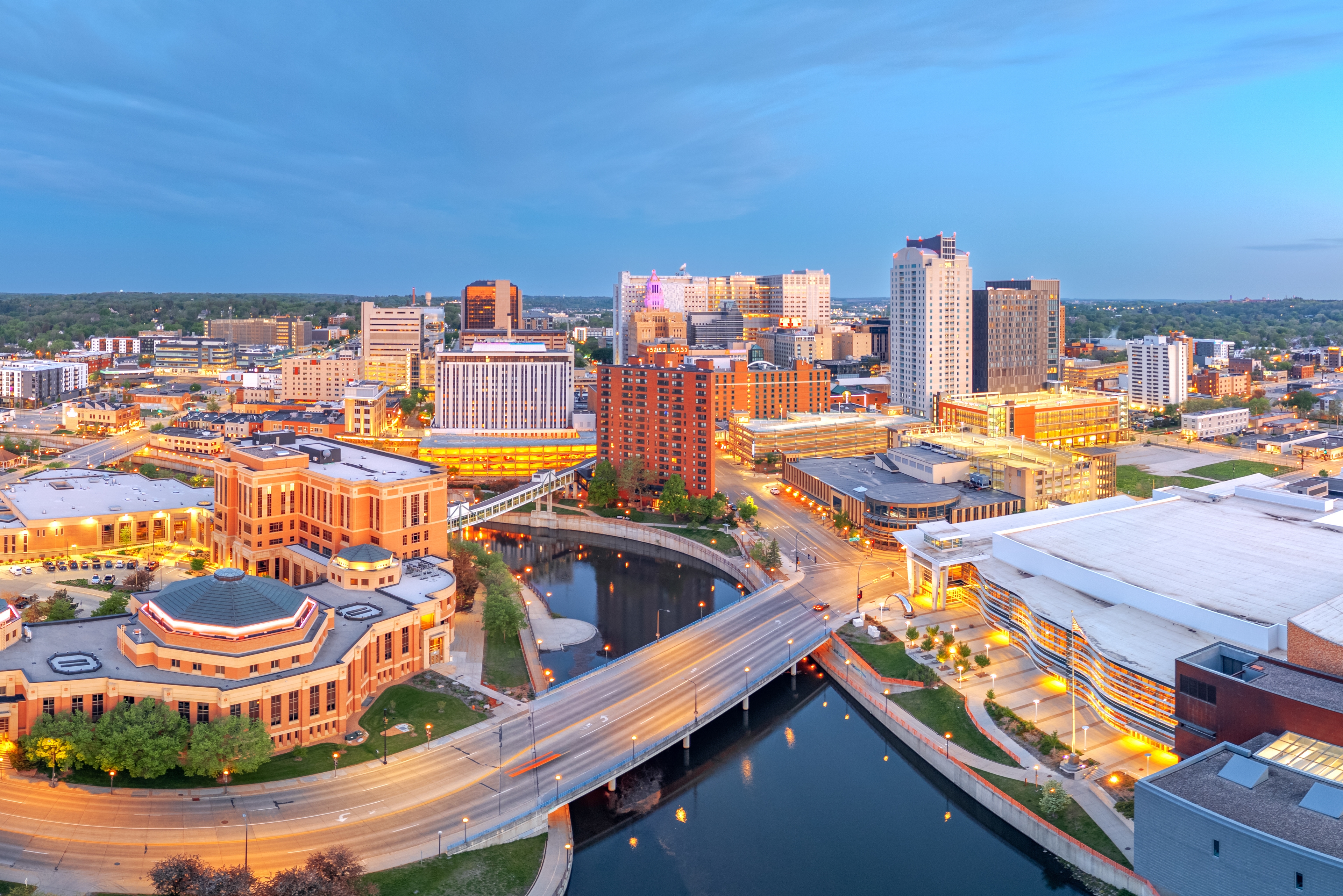 Aerial view of downtown Rochester, Minnesota at dusk with city skyline, bridges, and Zumbro River, representing local records management, storage, and shredding service coverage in the Rochester market.