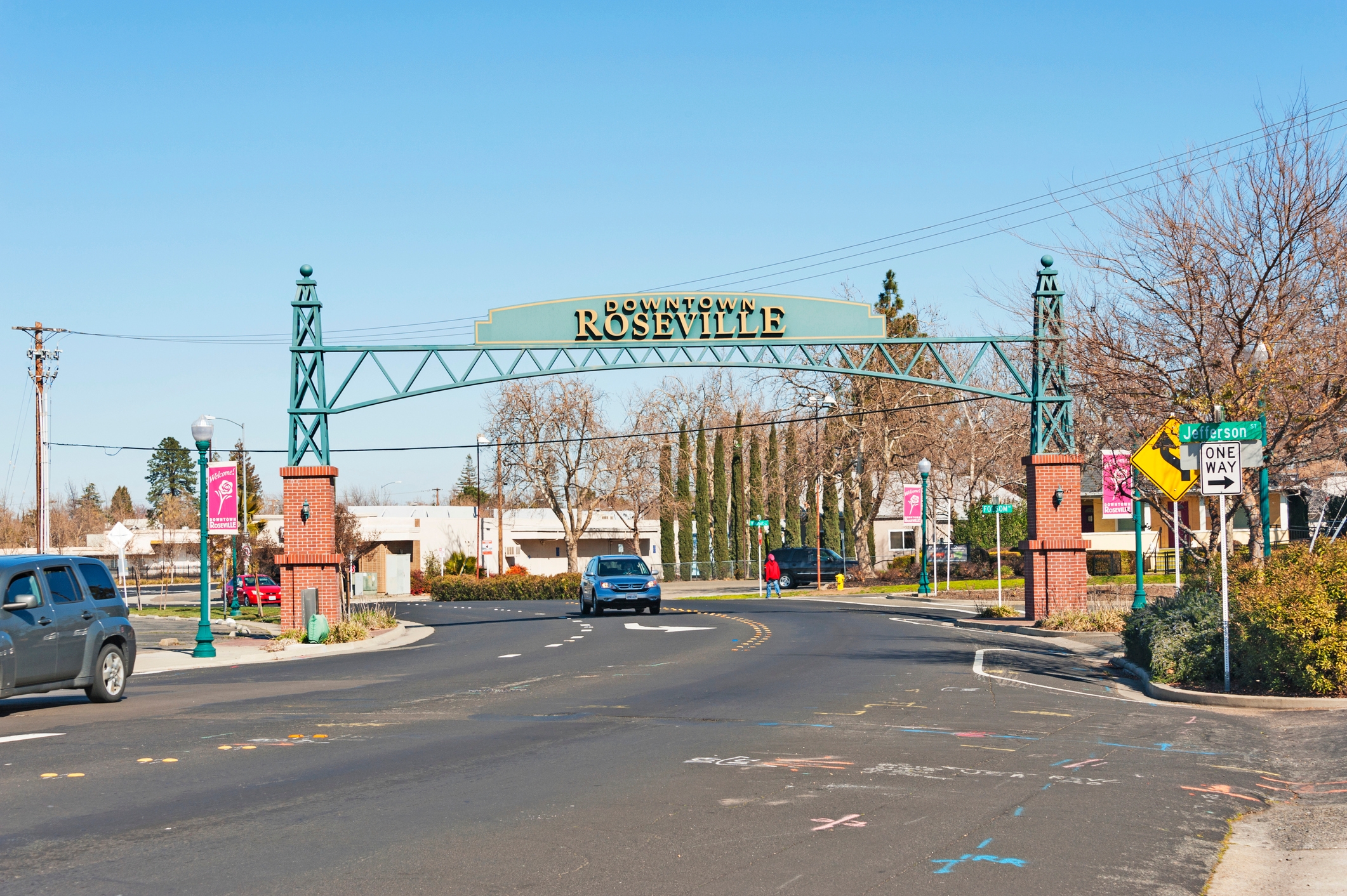 A street-level view of Downtown Roseville, California, featuring a decorative green archway with the name 'Downtown Roseville.'