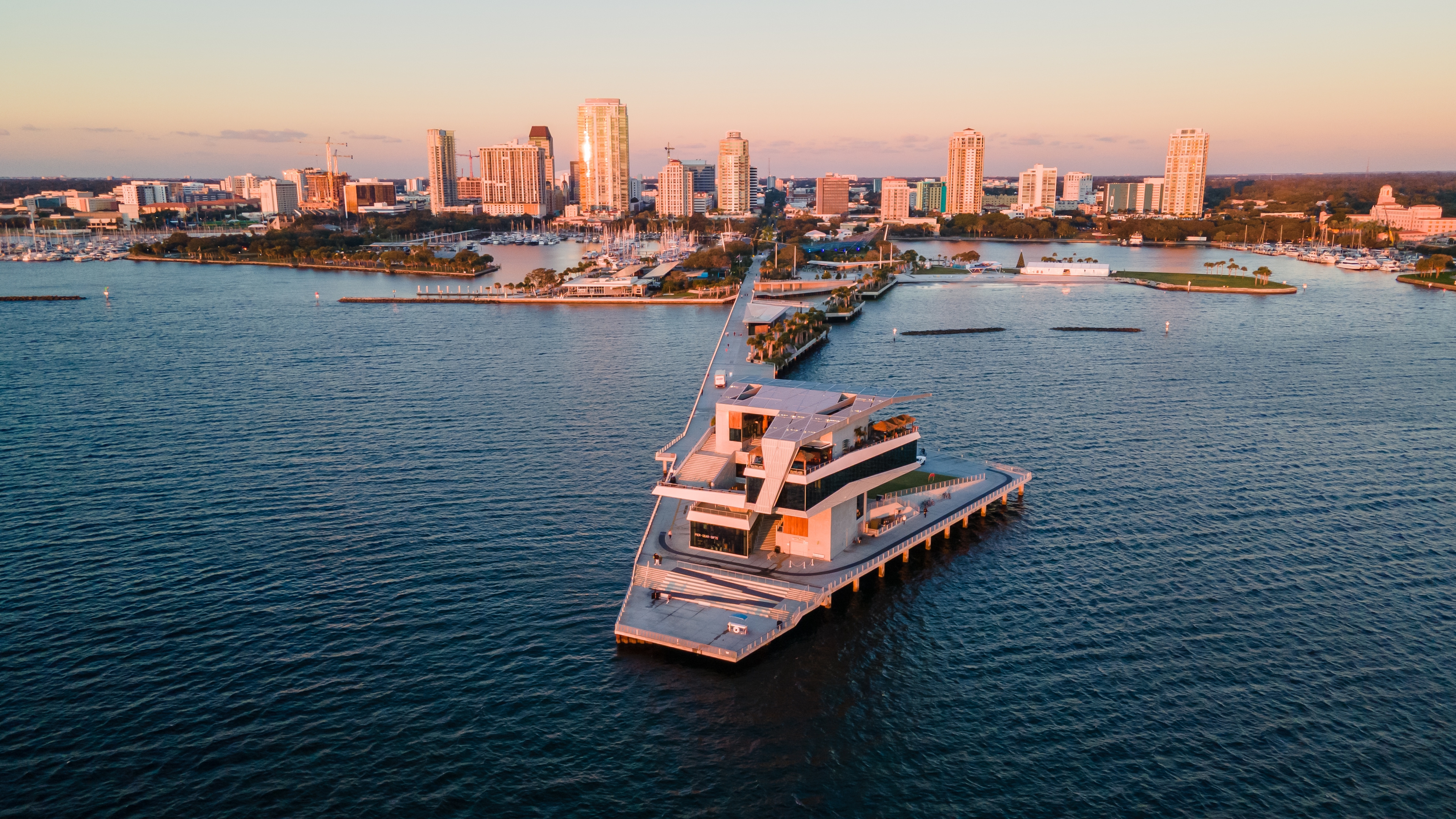 Aerial view of downtown St. Petersburg, Florida at sunset, featuring a waterfront pier, marina, and modern skyline