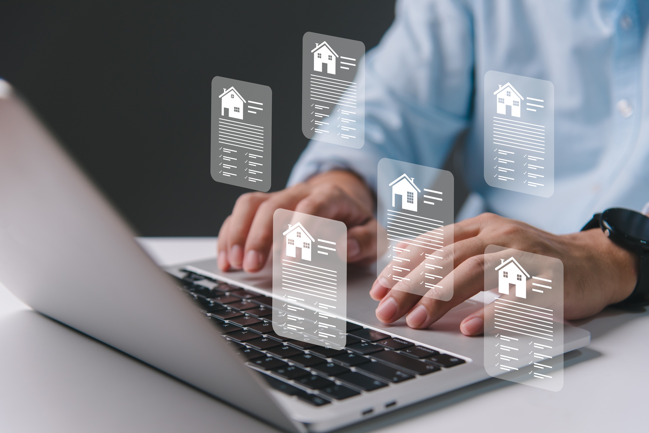 Person typing on a laptop with floating digital real estate documents, each featuring icons of houses and checklists, symbolizing property data or listings.