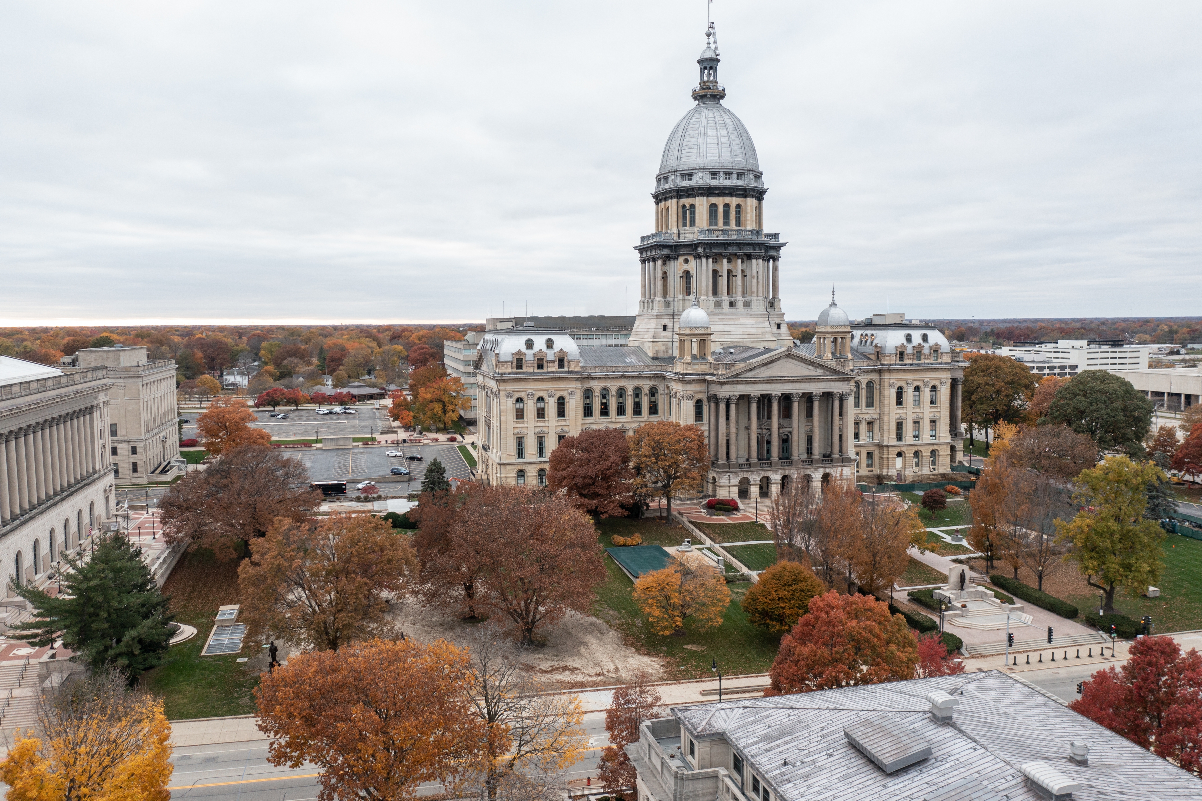 Aerial view of the Illinois State Capitol building in Springfield surrounded by colorful autumn trees and historic architecture.