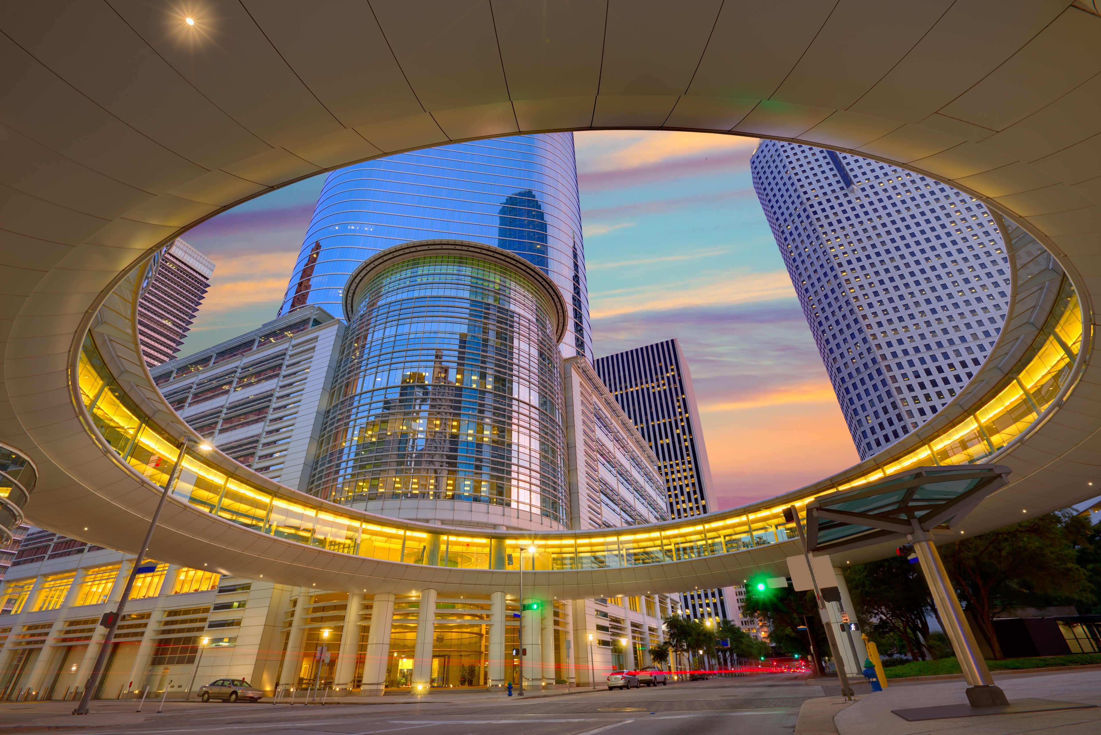 A striking circular skywalk frames the Houston skyline at sunset, showcasing the city’s modern architecture and vibrant urban atmosphere in downtown Texas.