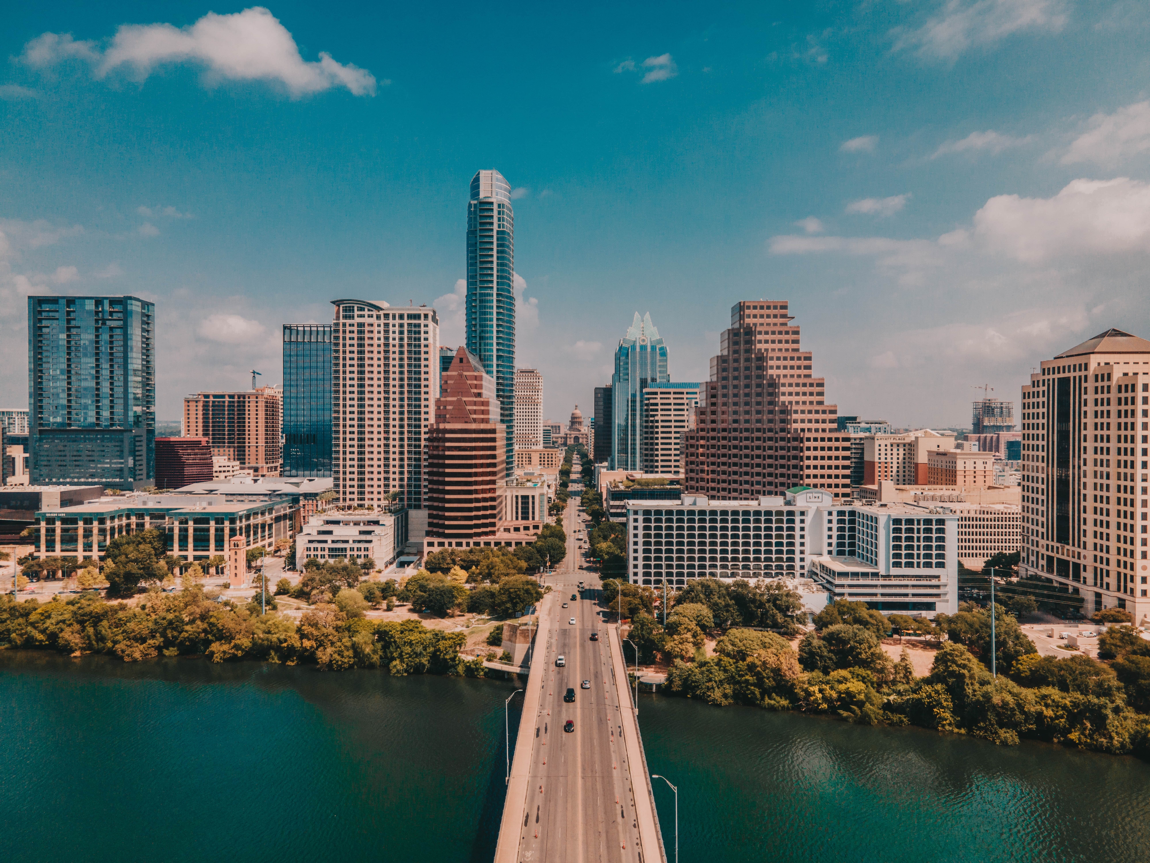 Downtown Austin skyline view from across the Colorado River, featuring modern high-rise buildings under a partly cloudy sky.