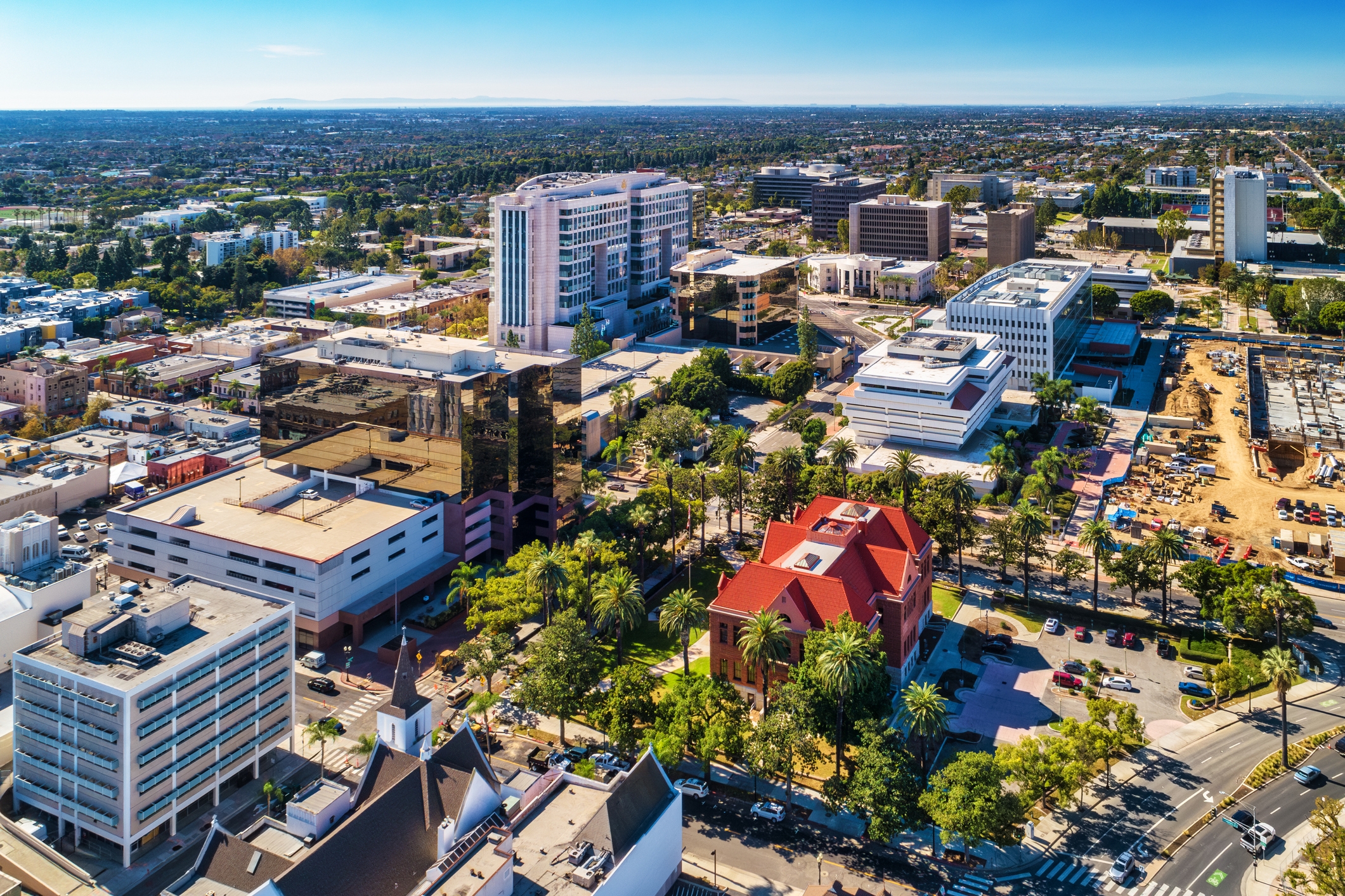 Downtown Santa Ana, California, aerial view featuring modern government buildings, historic architecture, and active development zones surrounded by palm trees.