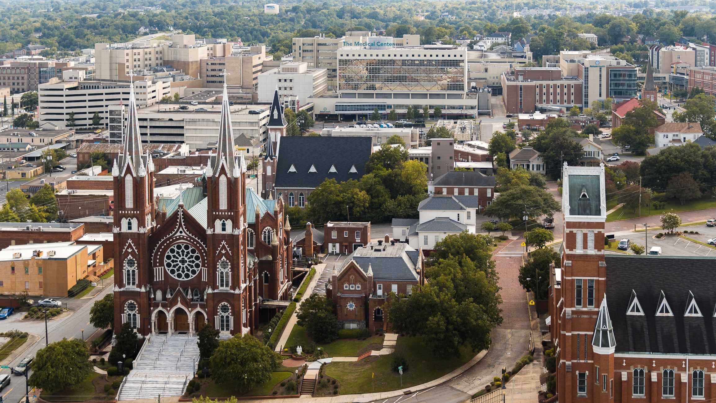 Aerial shot of downtown Macon, Georgia, highlighting its historic architecture, religious landmarks, and business district with the Medical Center in the background.