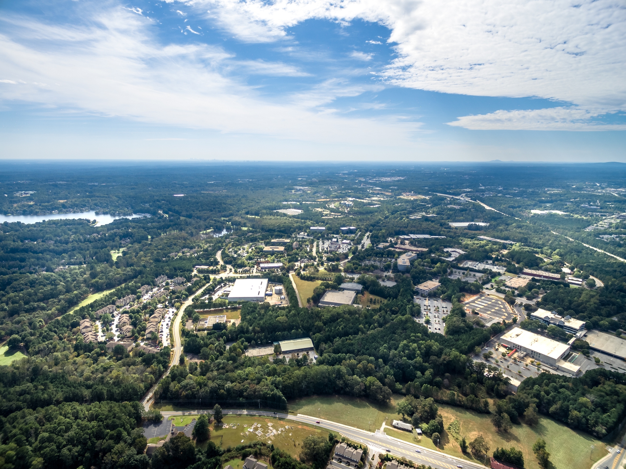 Aerial view of Sandy Springs, Georgia, highlighting its blend of business districts, residential areas, and natural surroundings, with a clear sky in the background.