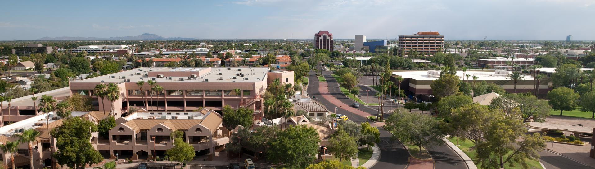 Panoramic view of downtown Mesa, Arizona showcasing a blend of office buildings, residential areas, and desert greenery under a clear blue sky.