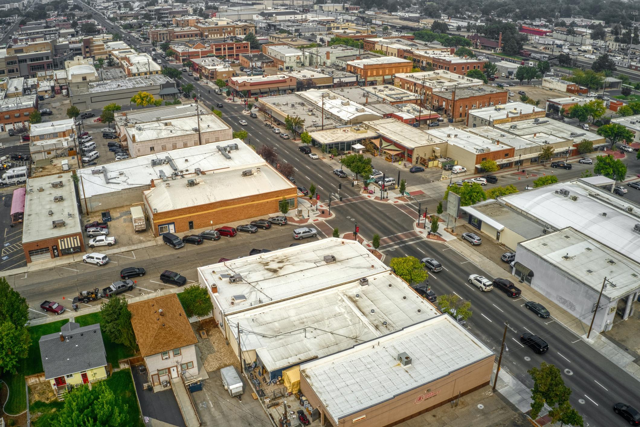 Downtown Nampa, Idaho, as seen from above, featuring small businesses with flat rooftops, intersecting roads, and parking areas. 