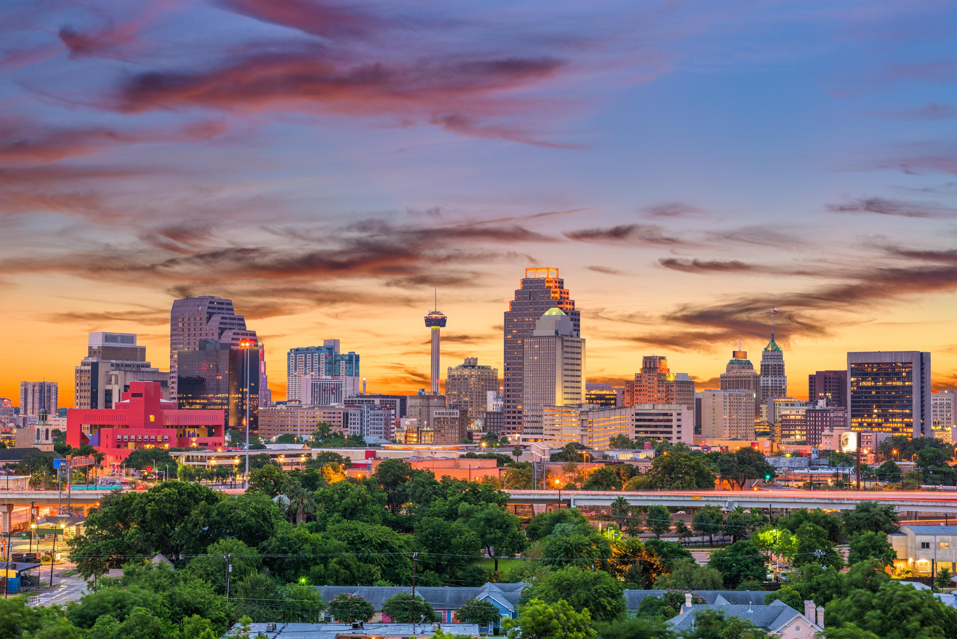 Colorful sunset over the San Antonio skyline, featuring the Tower of the Americas and a blend of modern and historic architecture across the vibrant Texas cityscape.