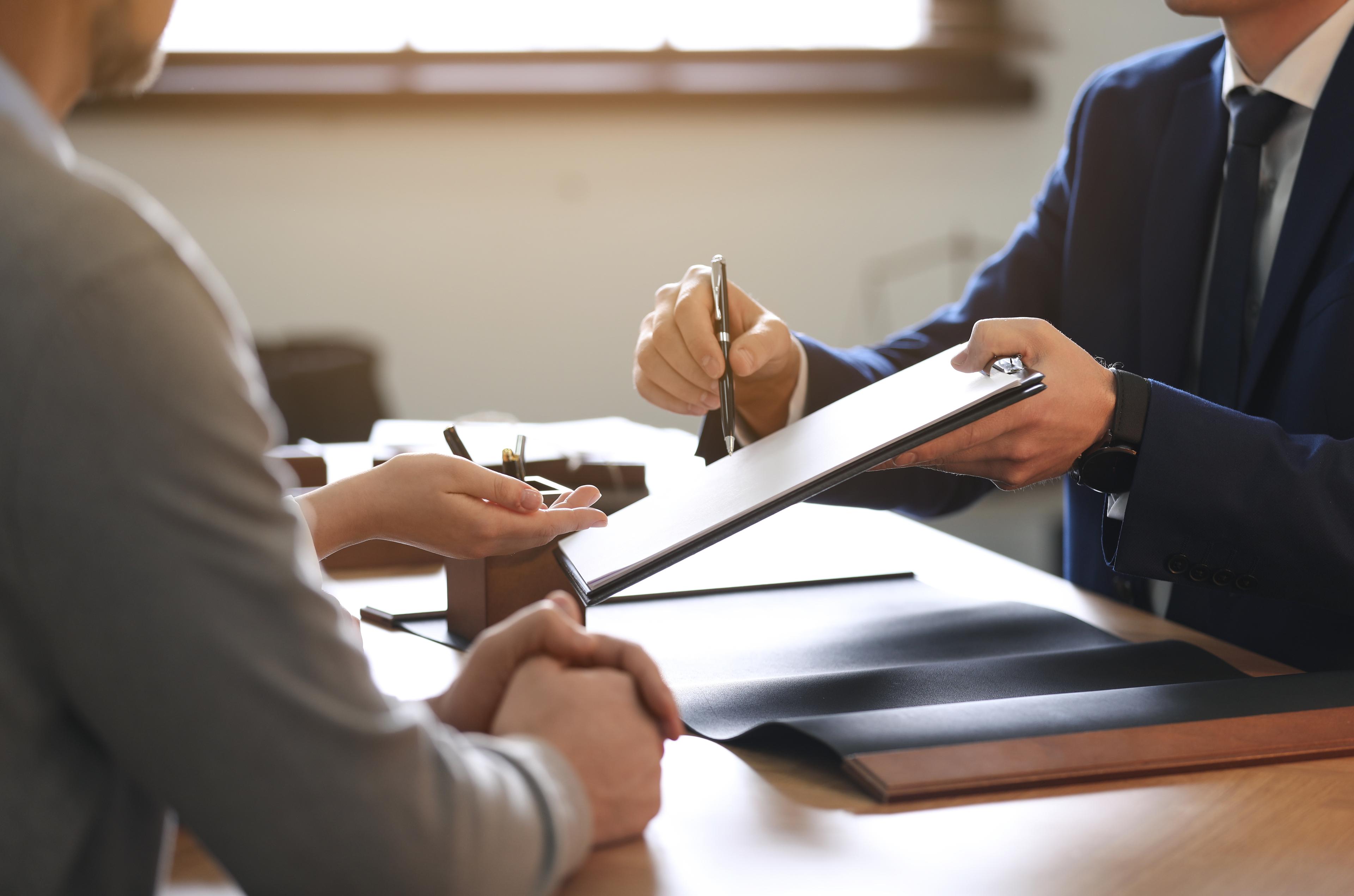 Professional meeting for document signing or contract agreement in office setting with advisor or legal consultant.