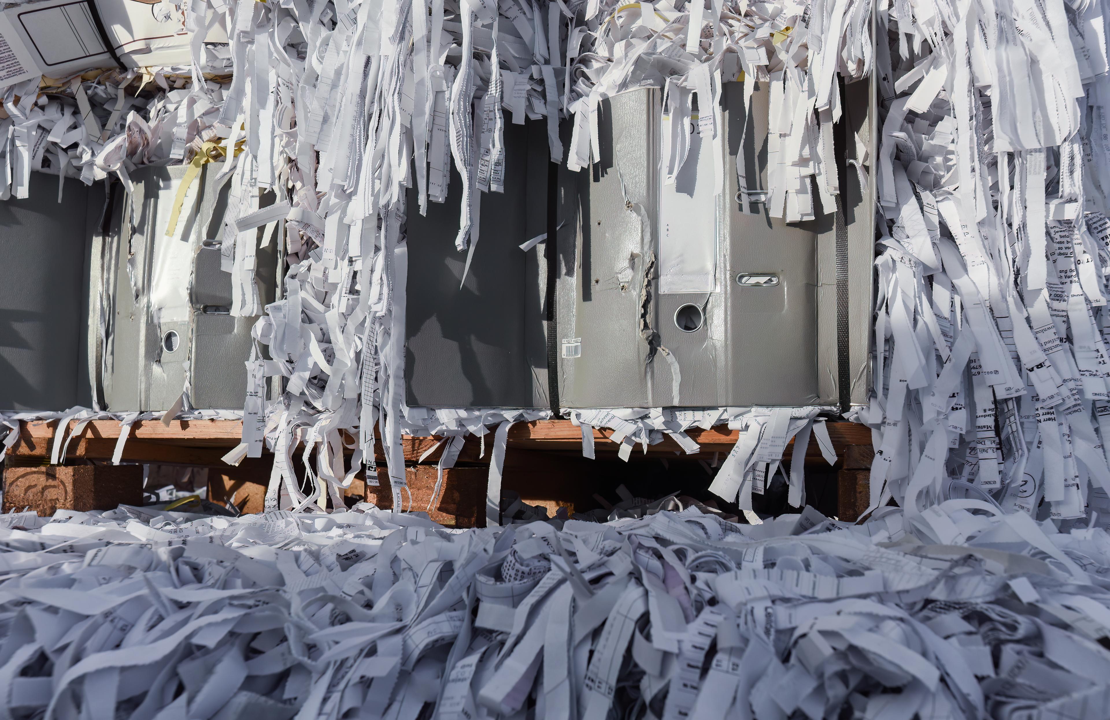 Shredded paper and destroyed file folders scattered on a wooden pallet, representing secure document destruction and compliance-focused records disposal.