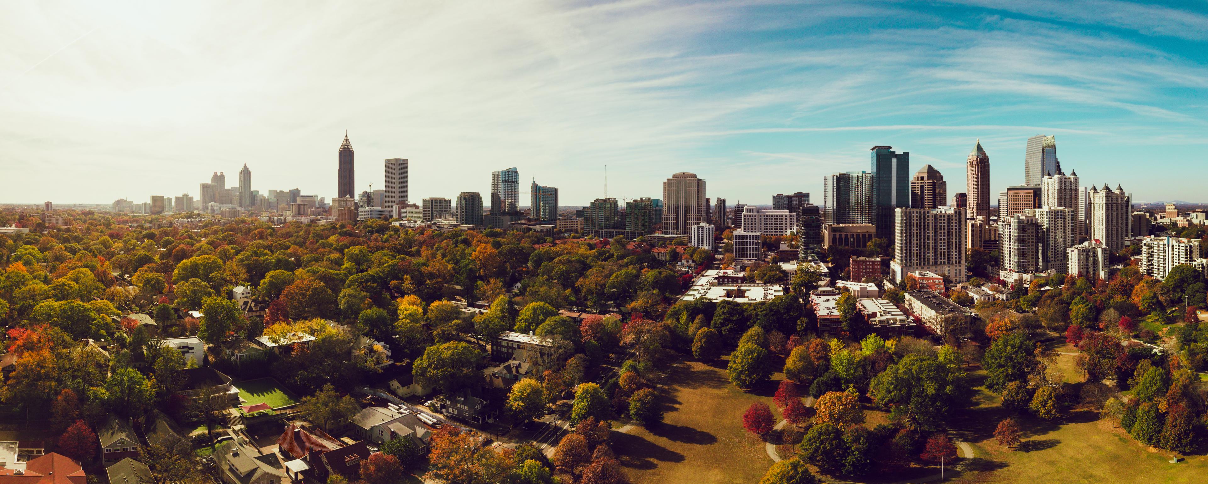 Panoramic aerial view of Atlanta, Georgia, showcasing Midtown’s skyline, autumn-colored trees, and Piedmont Park under a clear sky.