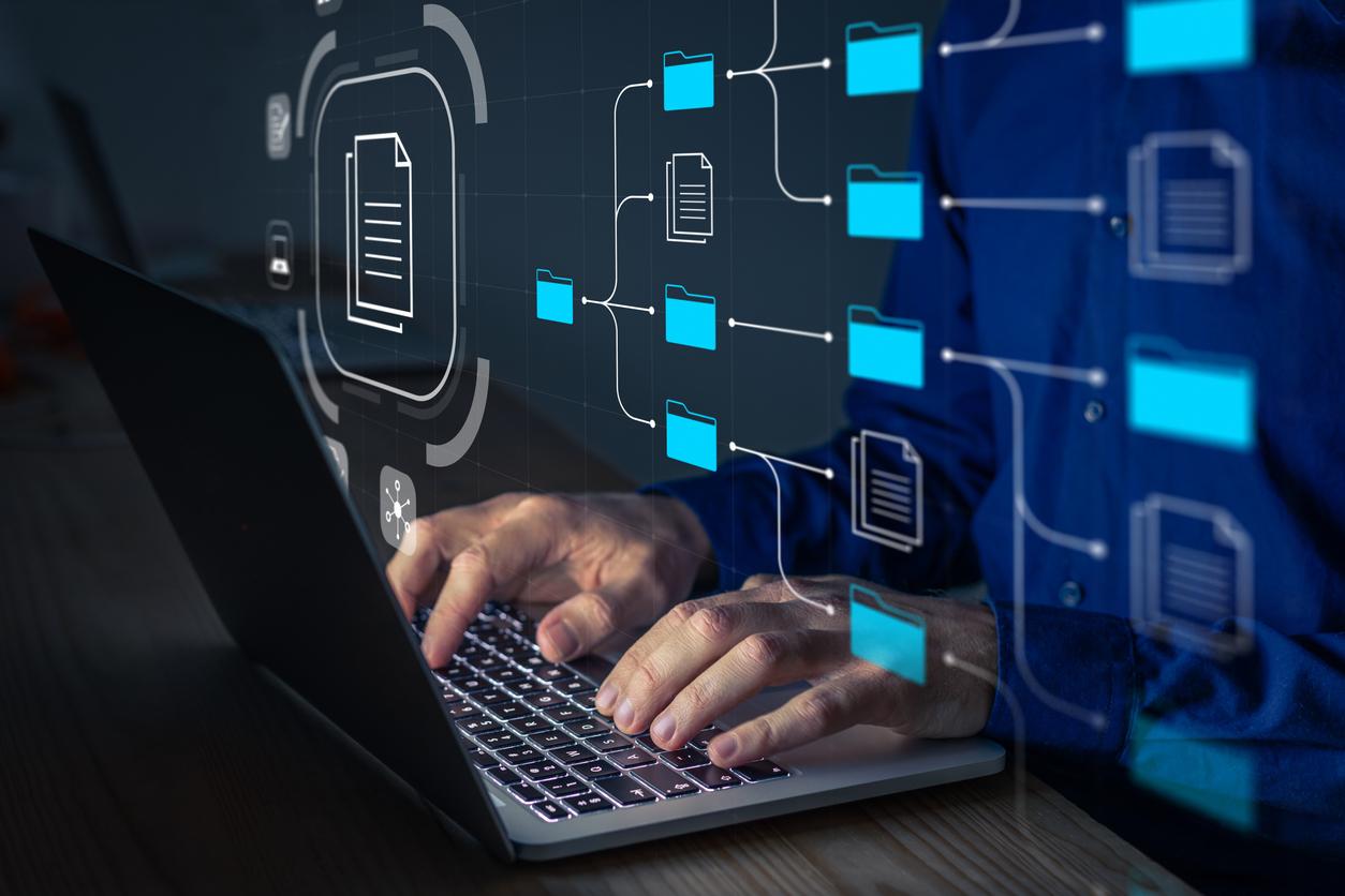 Person using a laptop with digital file folders and document icons overlay, representing electronic document management and secure data organization.