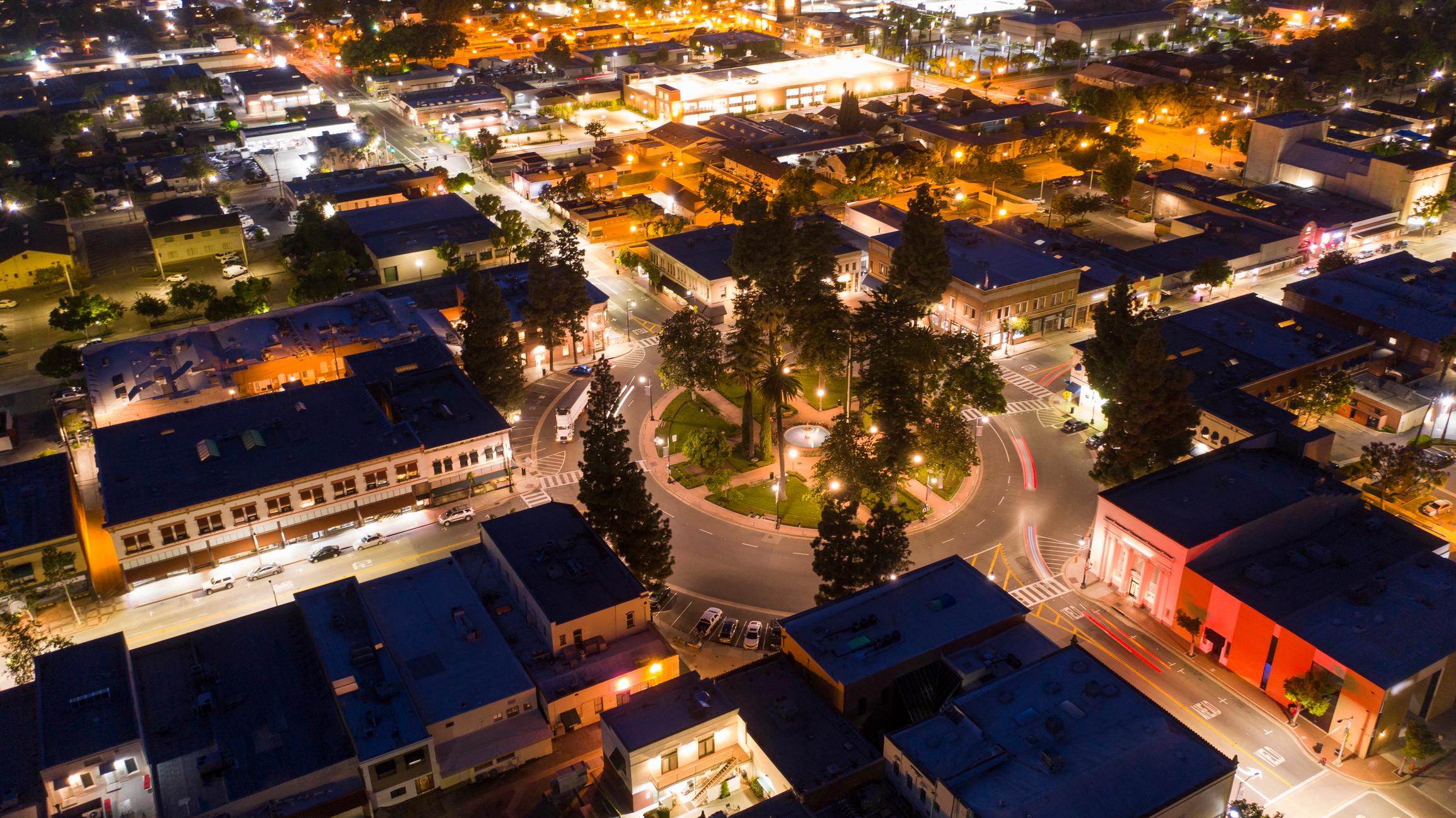Downtown Orange, California, illuminated at night with a central roundabout, historic buildings, and vibrant city lights.
