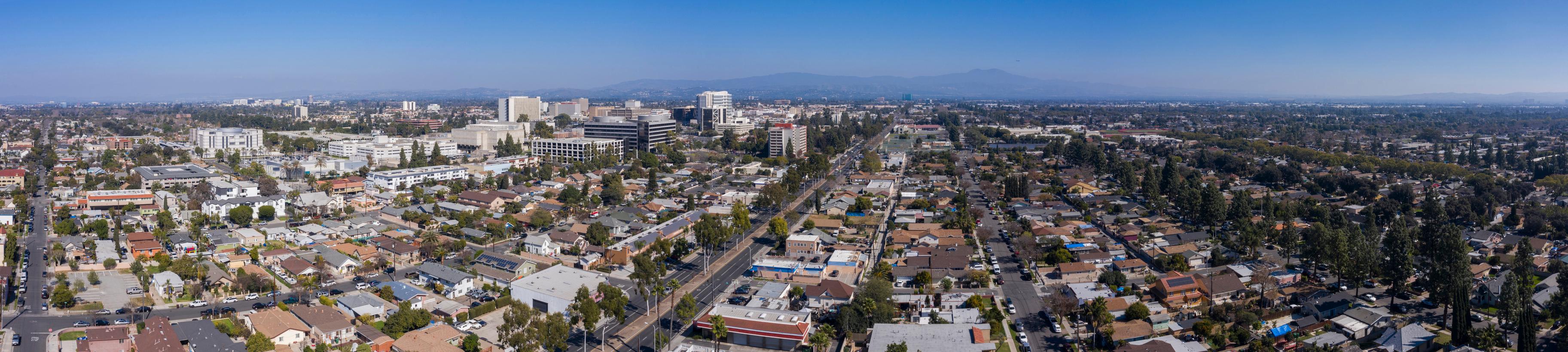 Wide-angle aerial view of Santa Ana, California, highlighting a blend of residential neighborhoods, government buildings, and downtown commercial areas under a clear sky.
